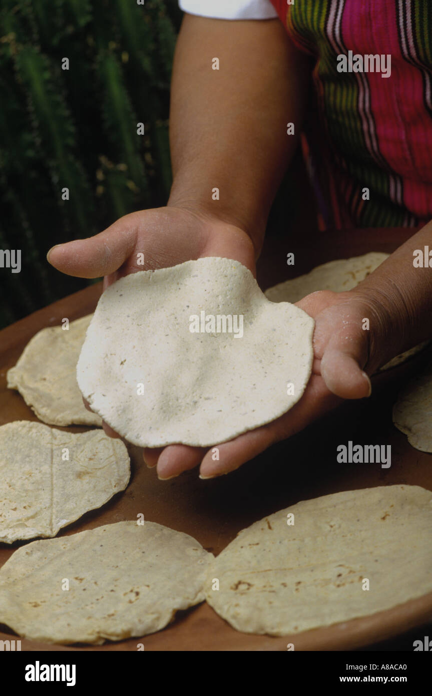 Mujer hace tortillas de maíz a mano y cocineros en un comal de barro
