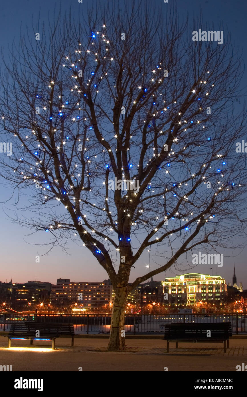 Orilla sur del río Támesis en penumbra con las luces del árbol. Londres, Inglaterra Foto de stock