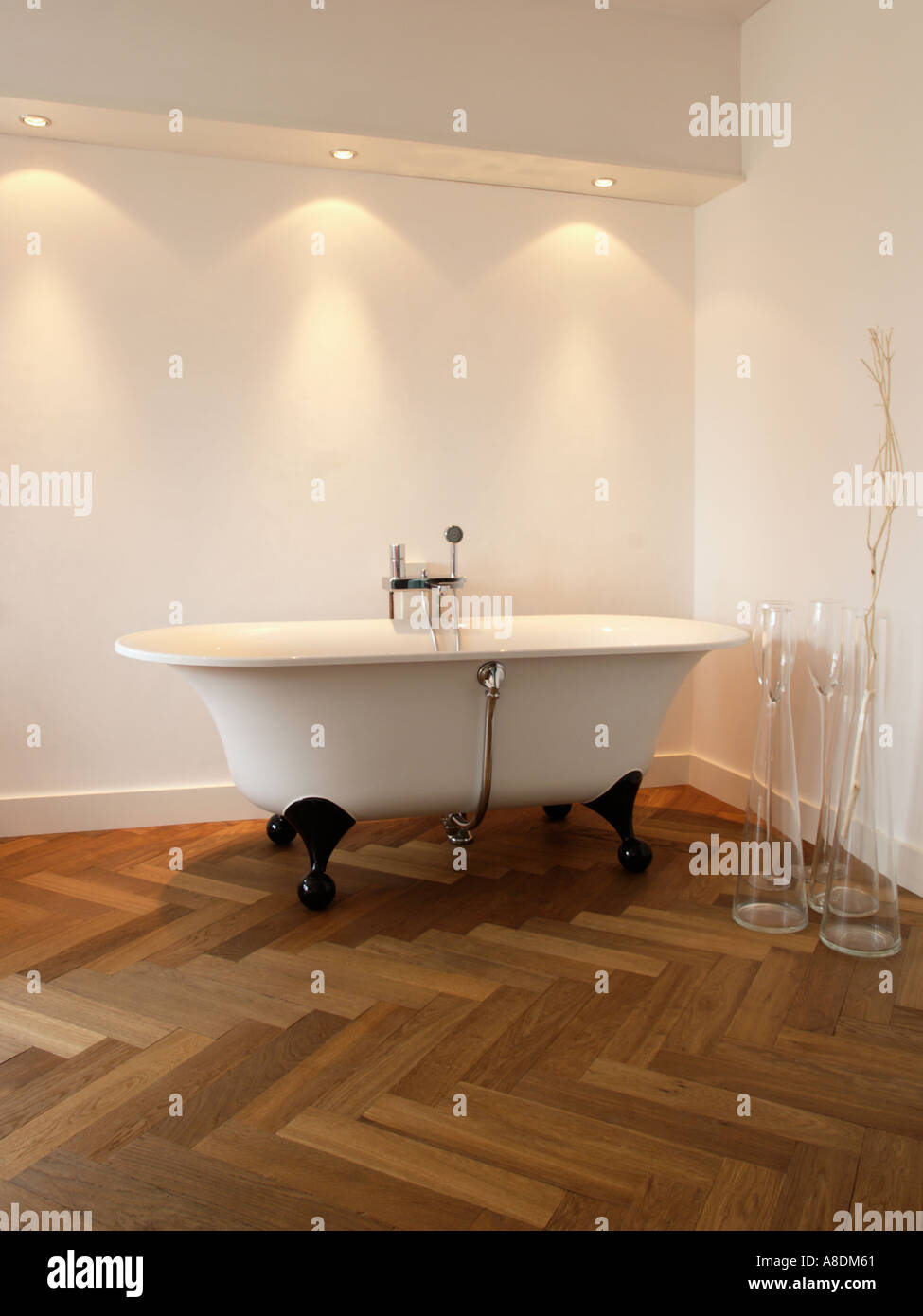 Baño de diseño con espiguilla iluminación halógena de parquet y baño independiente Foto de stock