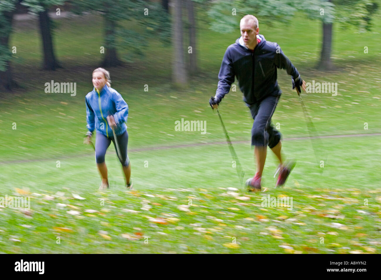 Dos nordic walker con palos y ropa deportiva caminar cuesta arriba en un  verde prado en el Jardín Inglés en Munich Fotografía de stock - Alamy