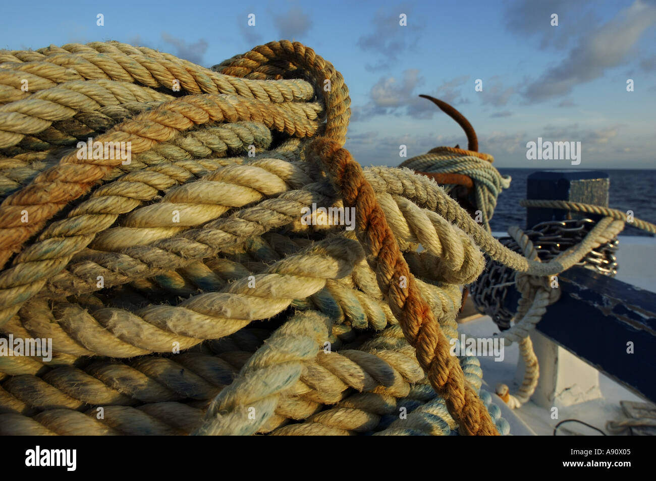 Bobinas de cuerda y ancla en la proa de un barco al atardecer Foto de stock