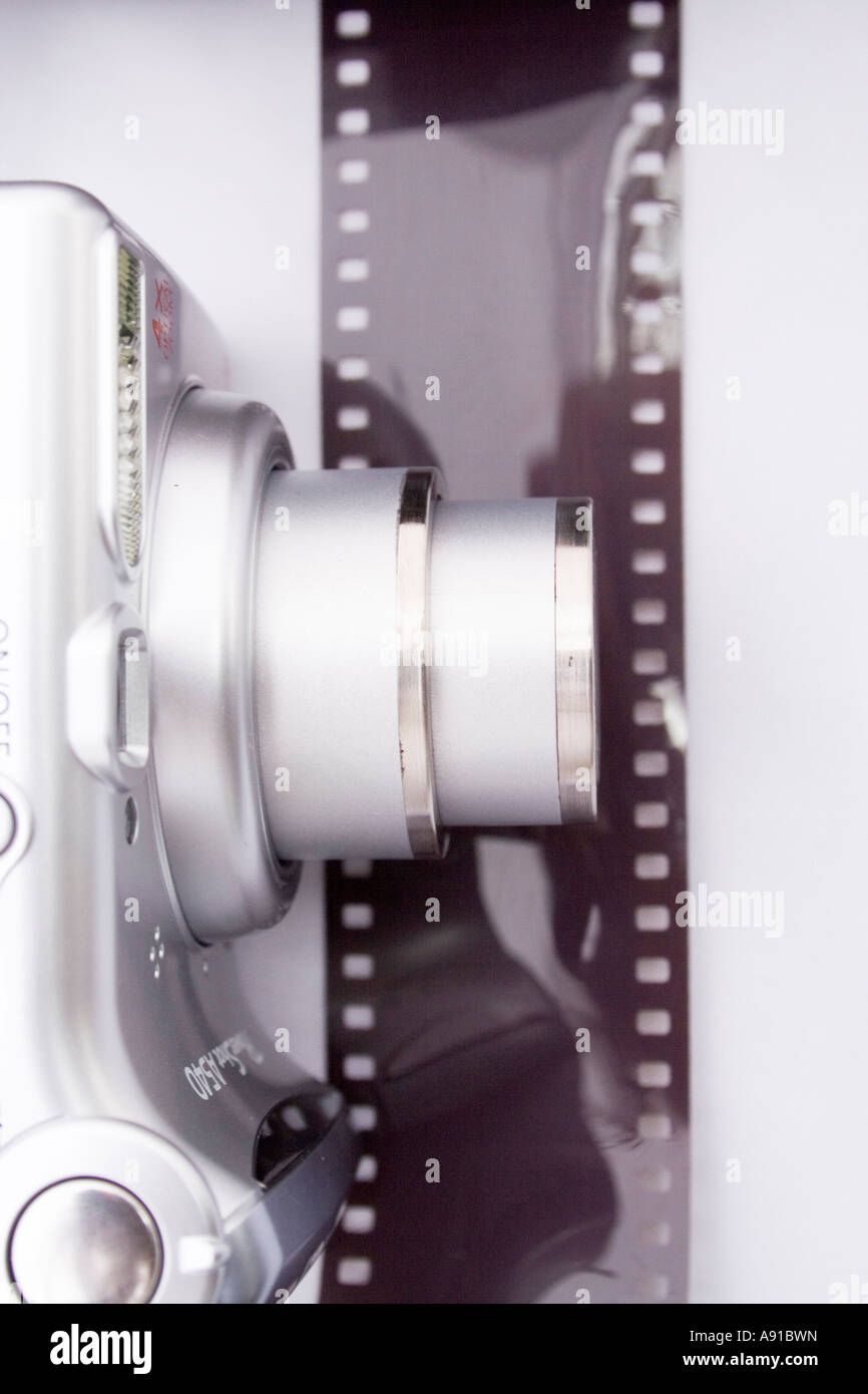 Una cámara digital compacta y el rollo de película. Tomadas en formato vertical sobre un fondo blanco. Lo moderno y lo clásico de la fotografía. Foto de stock