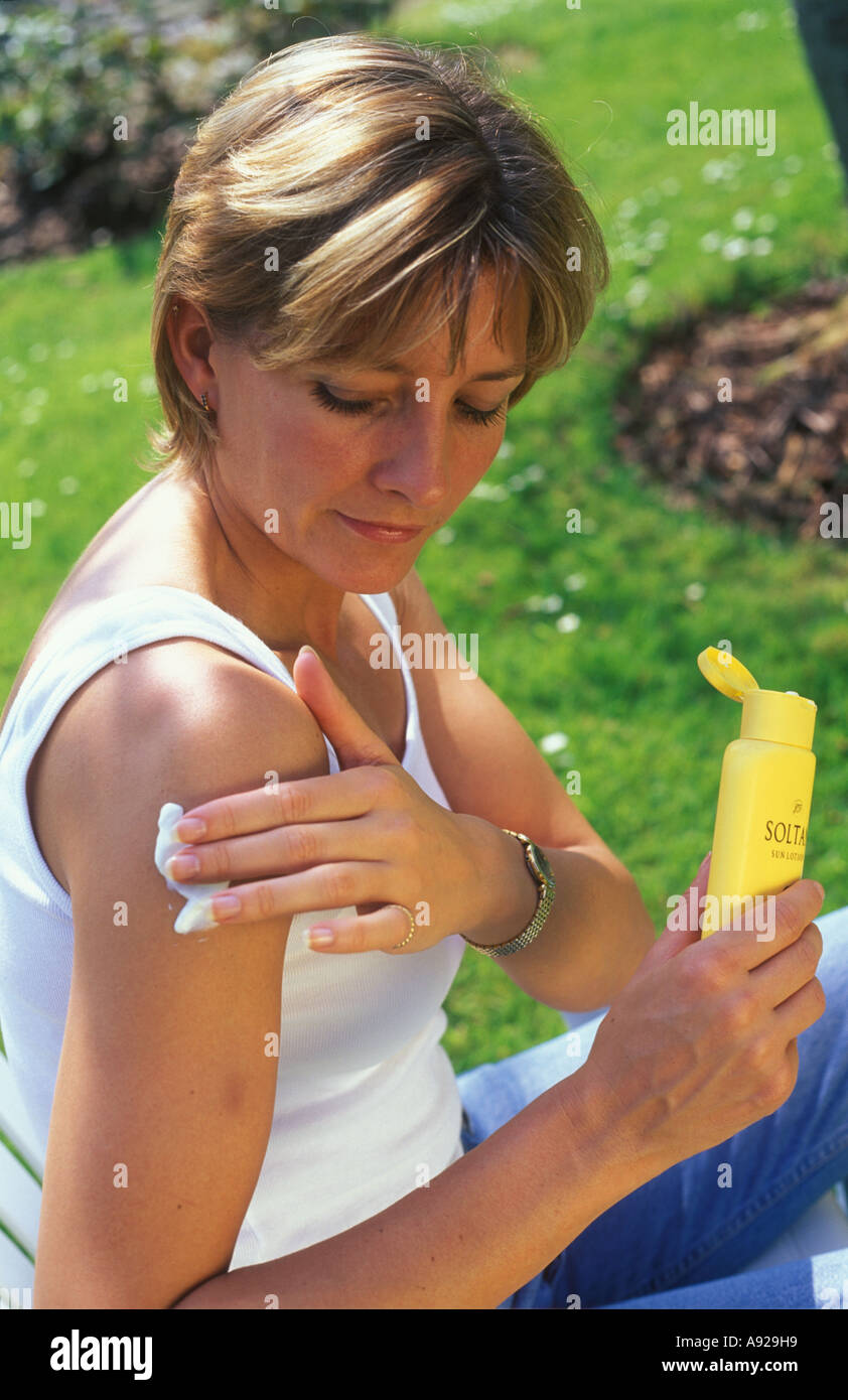 Mujer aplicar bronceador en el jardín Foto de stock