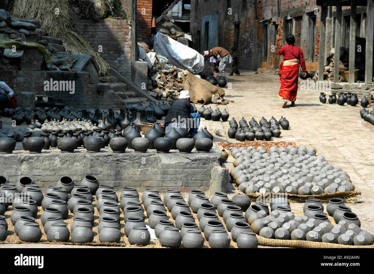 Alfarero trabajando entre muchos potes sacada de secado en la Plaza de los Alfareros Nepal Bhaktapur Foto de stock