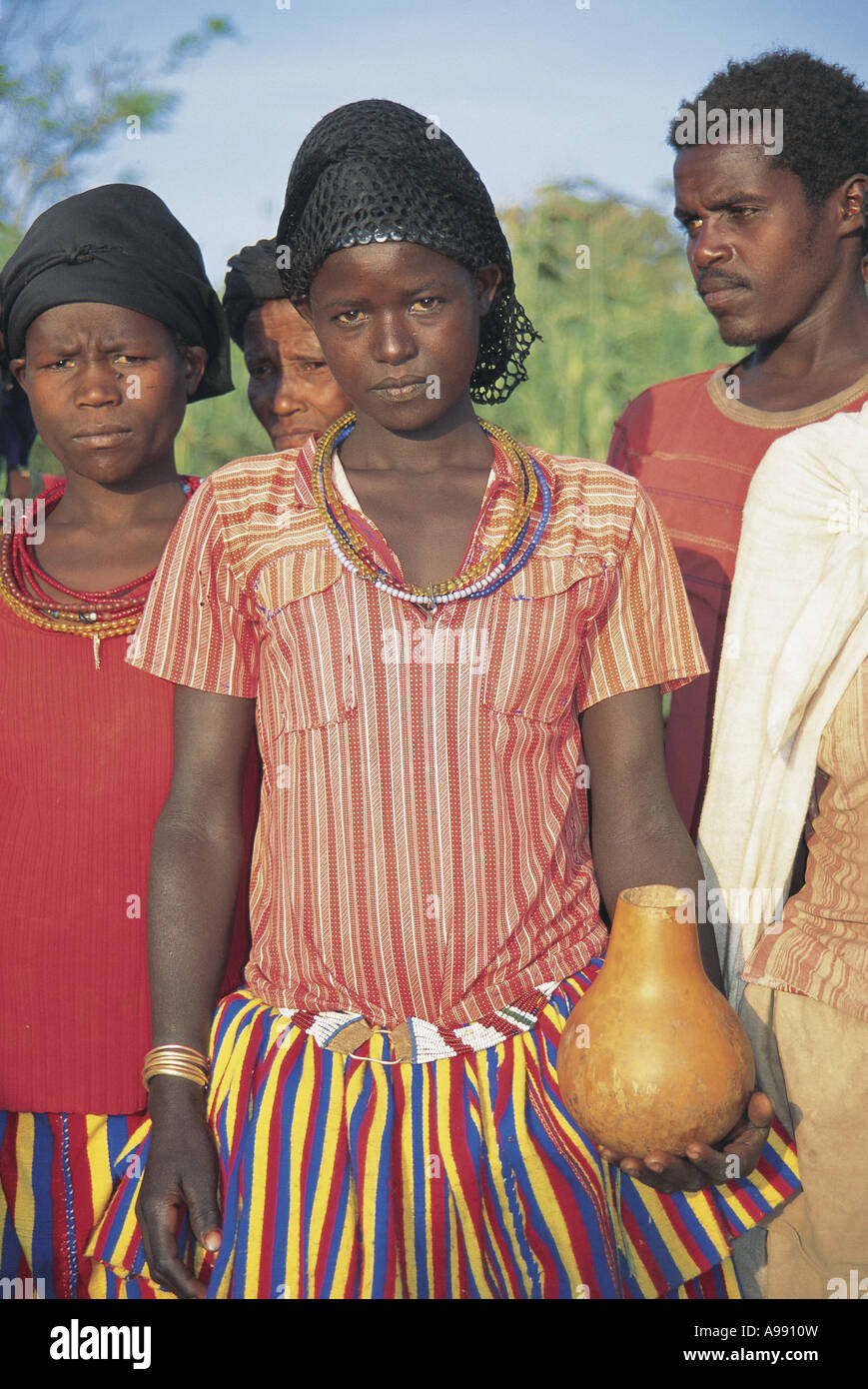 Chica en coloridos vestidos tradicionalmente la celebración de ordeño gourd Konso Etiopía Foto de stock