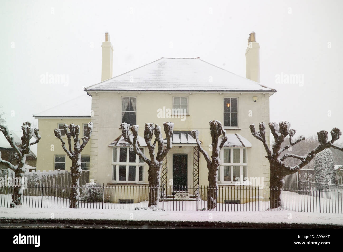 Casa con poda de árboles en la nieve Foto de stock