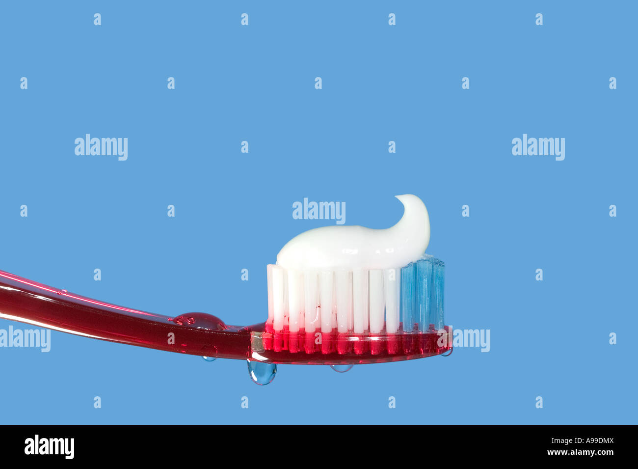 Cepillo de dientes y pasta roja aisladas sobre azul Foto de stock