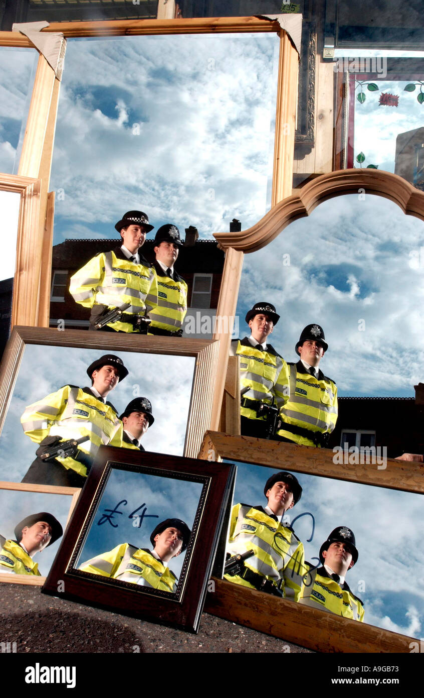 Dos agentes de policía uniformados. un macho y una hembra, en patrullas a pie refleja una y otra vez en los espejos en un escaparate Foto de stock