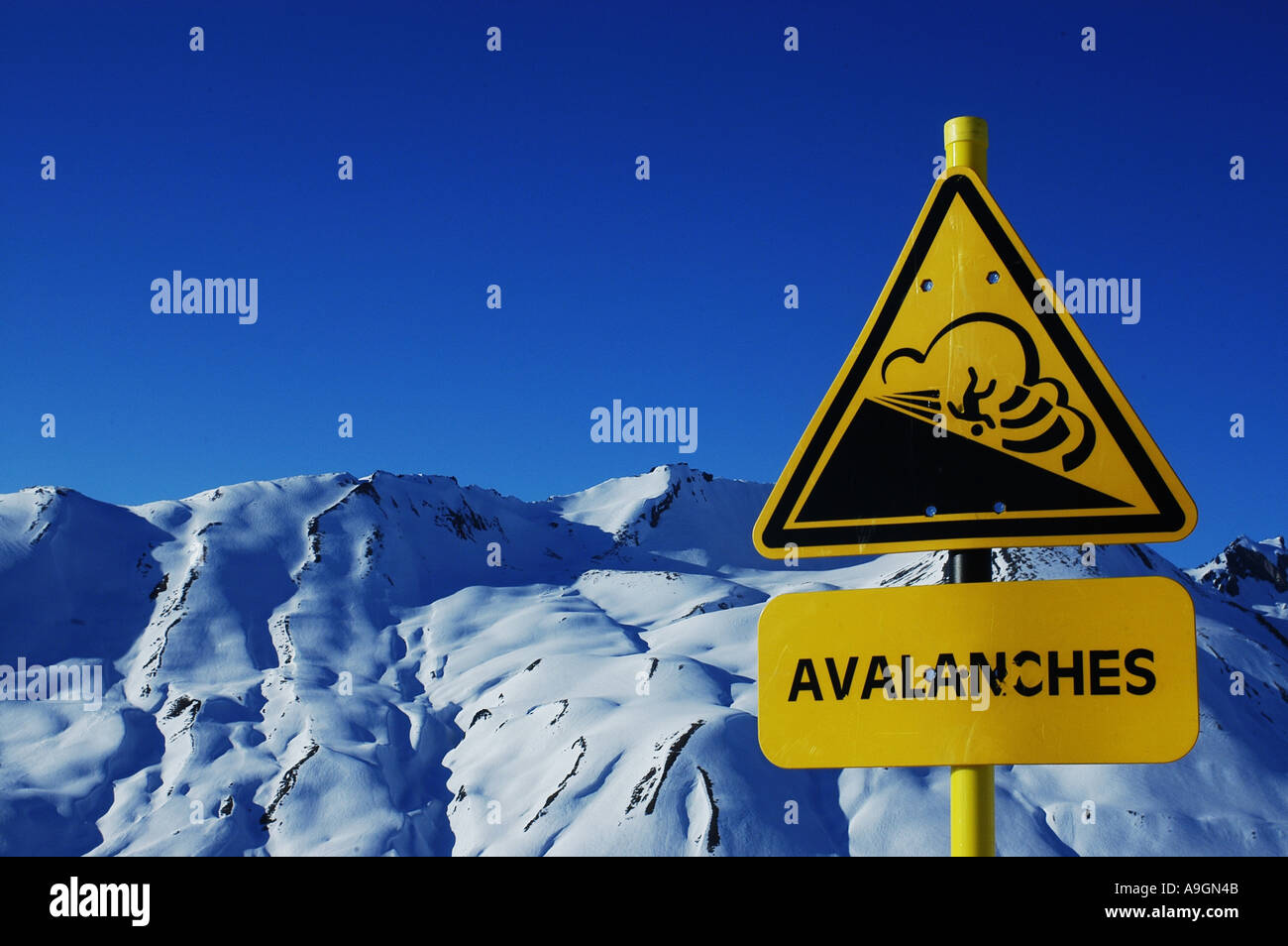Señal de peligro de avalanchas, con snowcovered paisaje alpino en segundo plano. Foto de stock