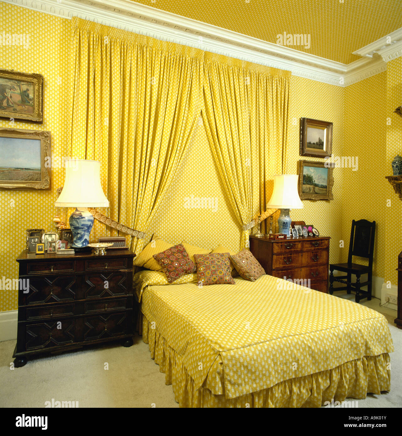 Las cortinas amarillas en la pared detrás de la cama con sábanas de color  amarillo a amarillo dormitorio con armarios de caoba en ambos lados de la  cama Fotografía de stock -