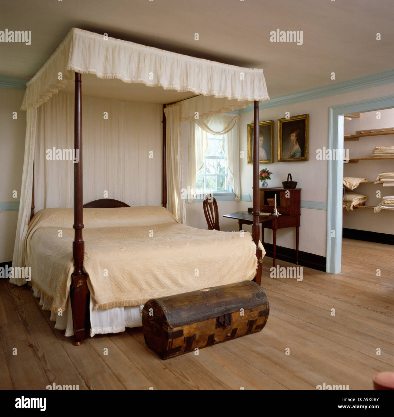 Antigua cama con dosel con cortinas de color crema y ropa de cama en el  país dormitorio con muebles antiguos de pecho y piso de madera Fotografía  de stock - Alamy