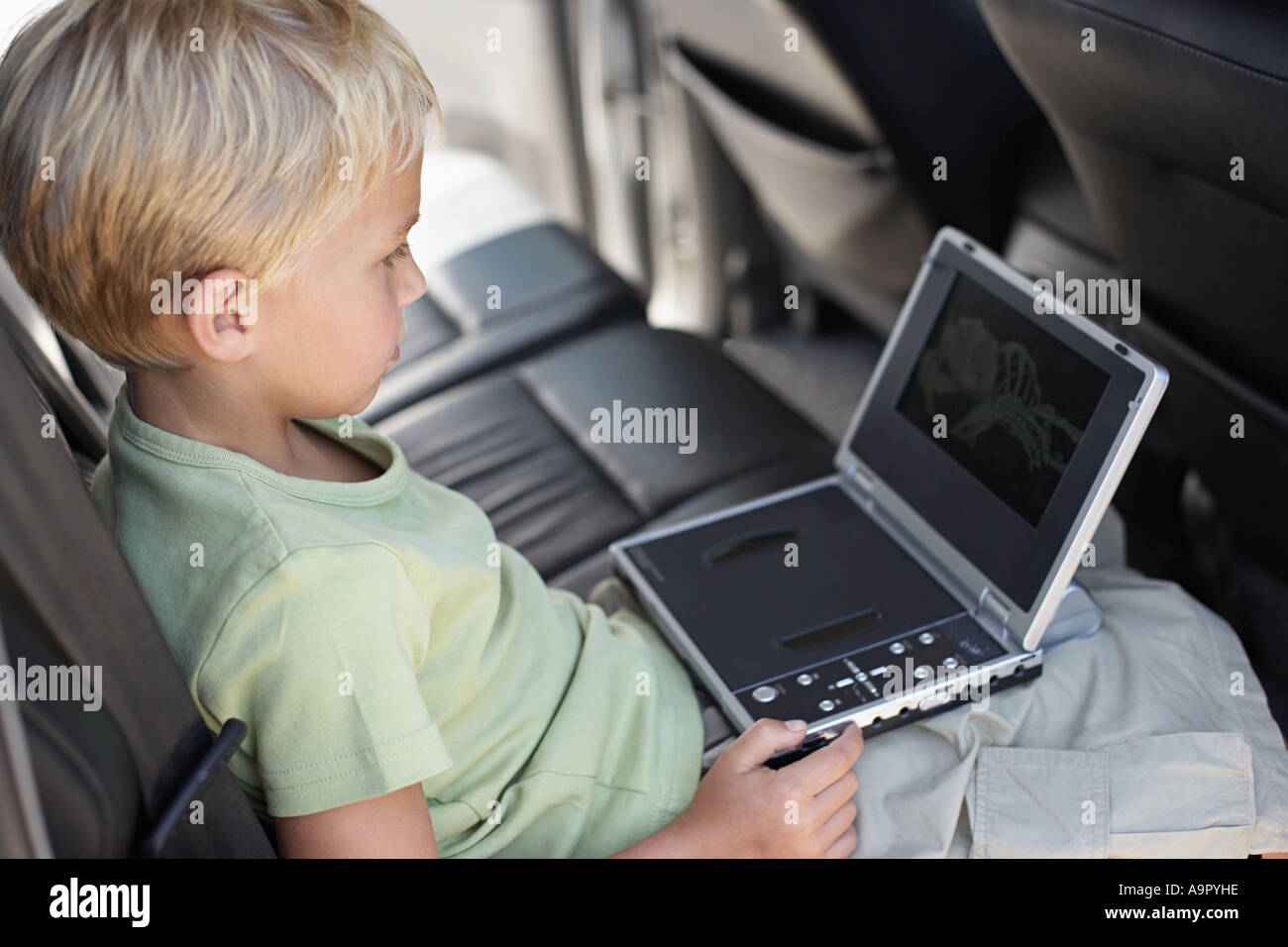 Muchacho sentado en el coche con el reproductor de DVD portátil Fotografía  de stock - Alamy