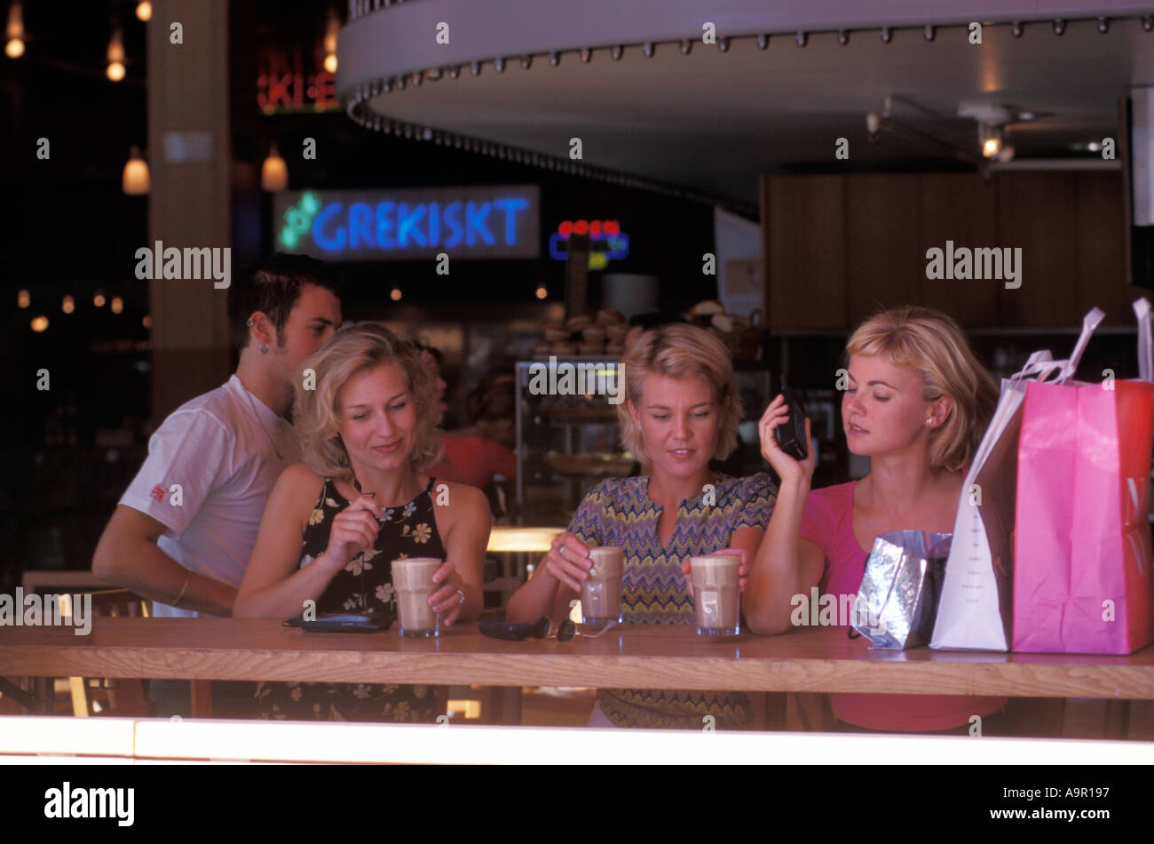 Tres mujeres con café y teléfonos celulares en Estocolmo café en la acera Foto de stock