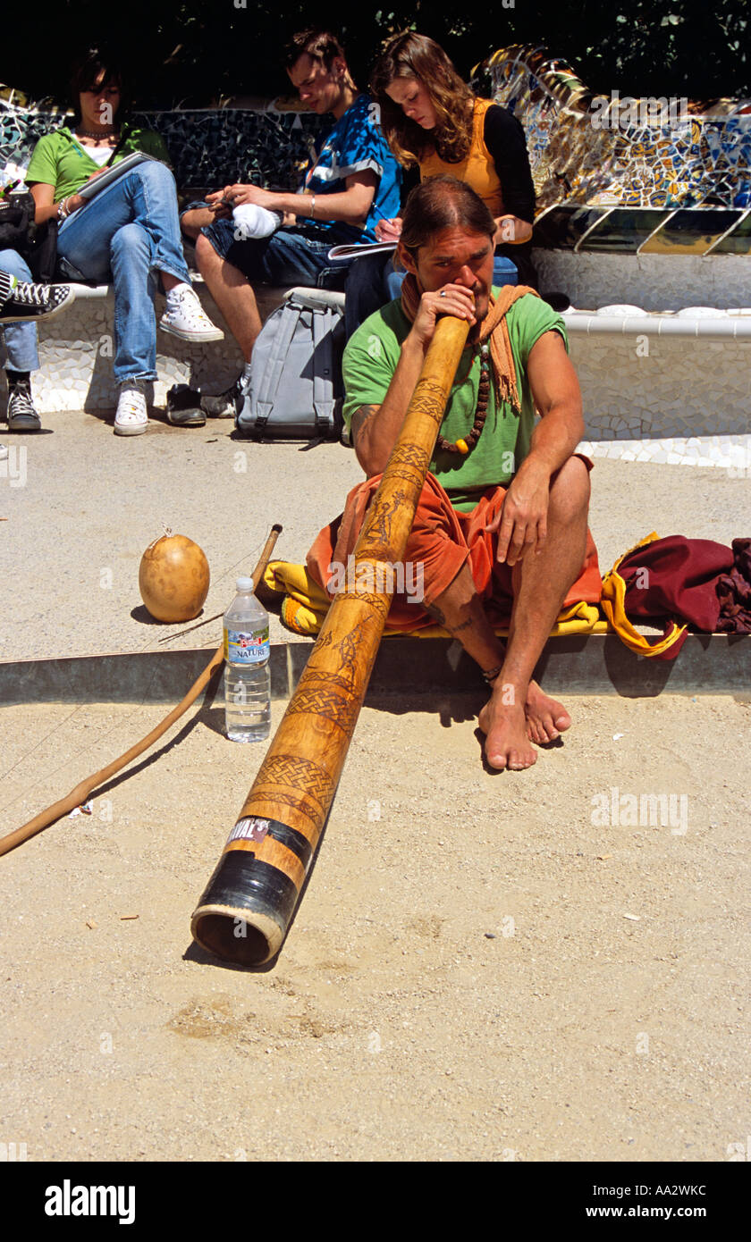 Hombre tocando el didgeridoo en frente de la famosa cerámica de Gaudí