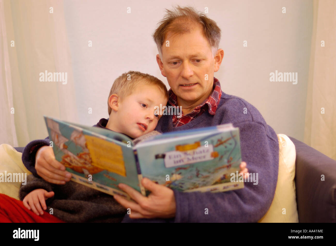 Padre leyendo a su pequeño niño de cinco años un libro de imágenes foto-libro Foto de stock