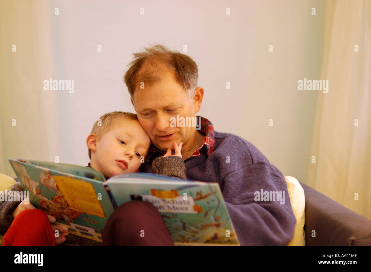 Padre leyendo a su pequeño niño de cinco años un libro de imágenes foto-libro Foto de stock