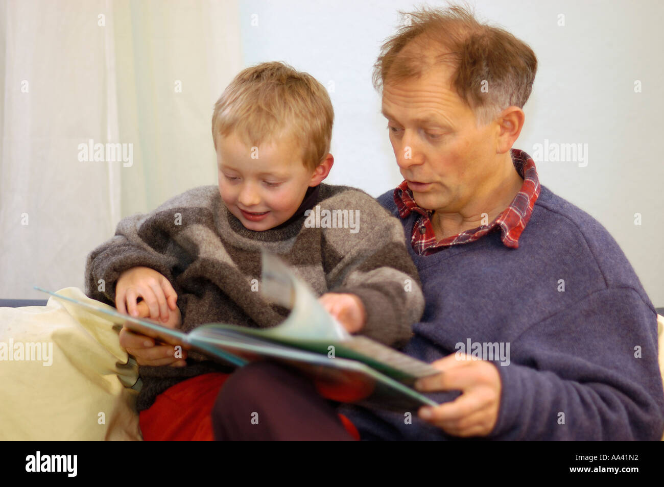 Padre leyendo a su pequeño niño de cinco años un libro de imágenes foto-libro Foto de stock