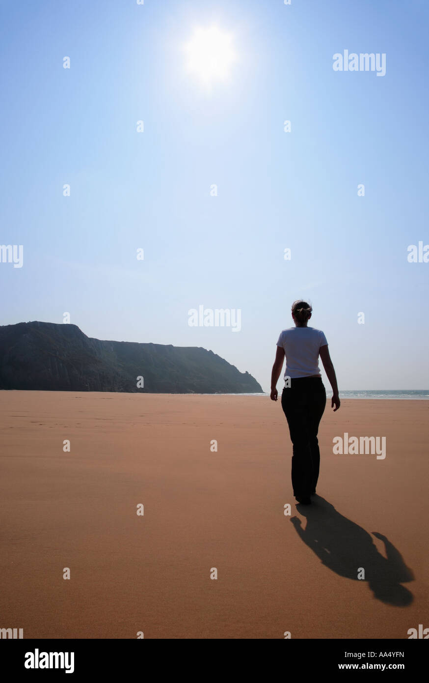 Mujer joven caminando por la playa en la Bahía de tres acantilados en el sur de Gales Gower Foto de stock