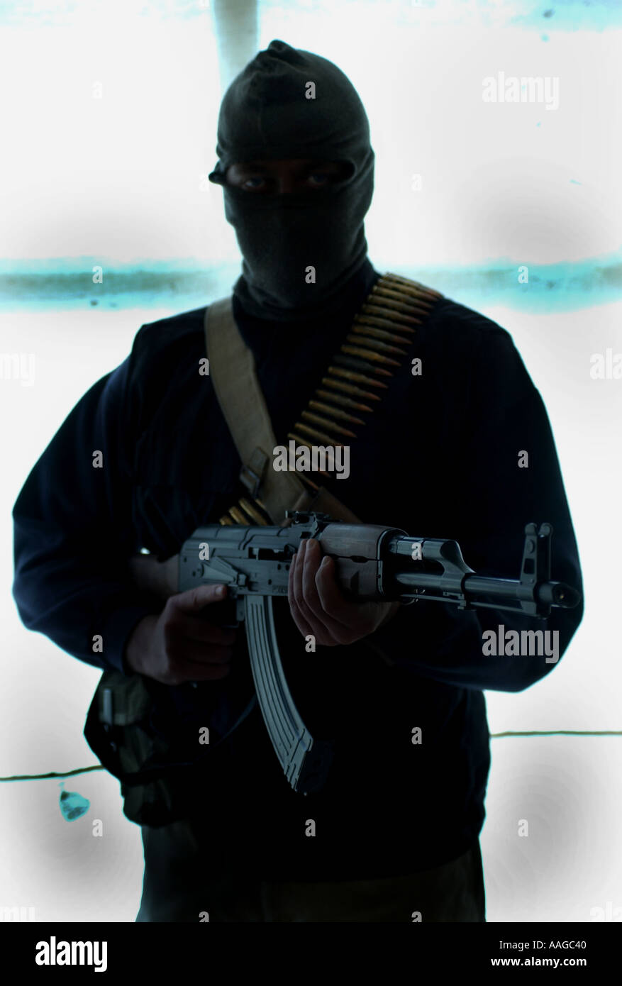 Un terrorista ataviado con un pasamontañas con un rifle Kalashnikov AK47 y un cinturón de balas Foto de stock