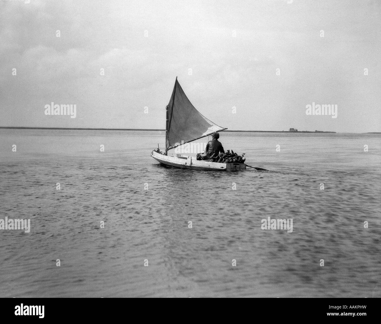 1920 HOMBRE EN PEQUEÑOS GATO barco repleto con pato señuelos ir caza BARNEGAT BAY Foto de stock