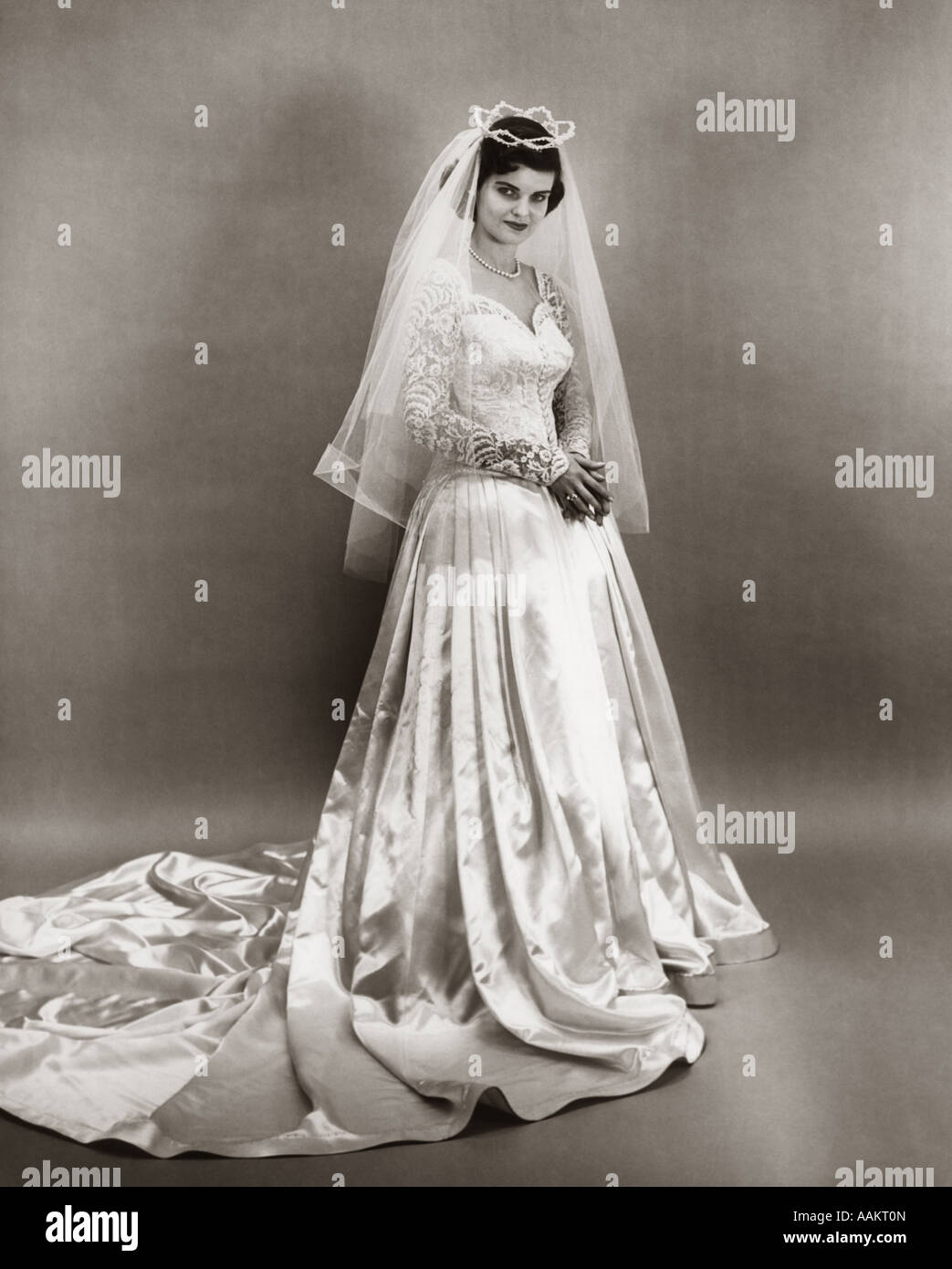 1950 Retrato de longitud completa permanente novia vestidos de satén y  encaje vestido de novia VELO Y TIARA mirando a la cámara Fotografía de  stock - Alamy