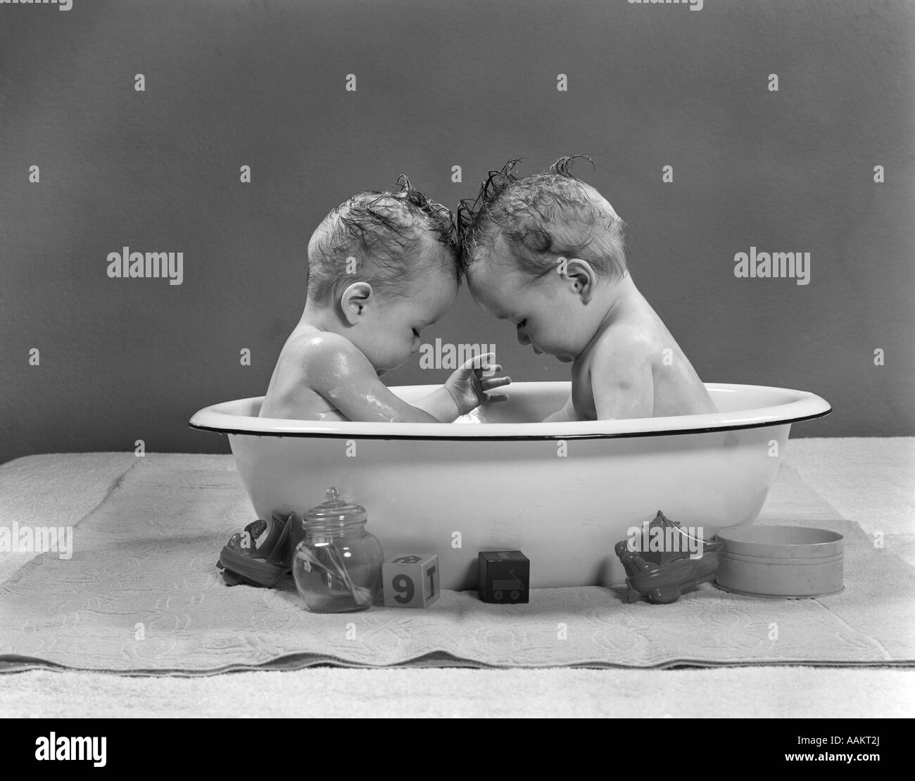 1950 TWIN BEBÉS sentados frente a frente en bañera metálica Foto de stock