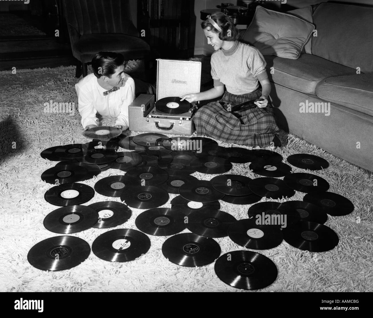 1950 la pareja de adolescentes jugando muchos registros de música DISTRIBUIDOS EN SALÓN PISO Foto de stock