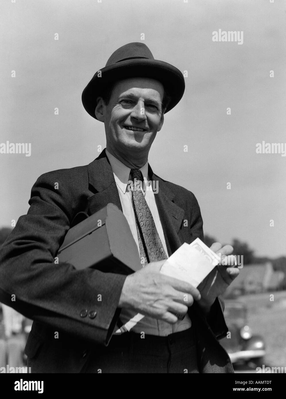 1930 El hombre en traje sombrero con FIAMBRERA bajo el brazo sosteniendo un sobre con cheque Fotografía de stock - Alamy