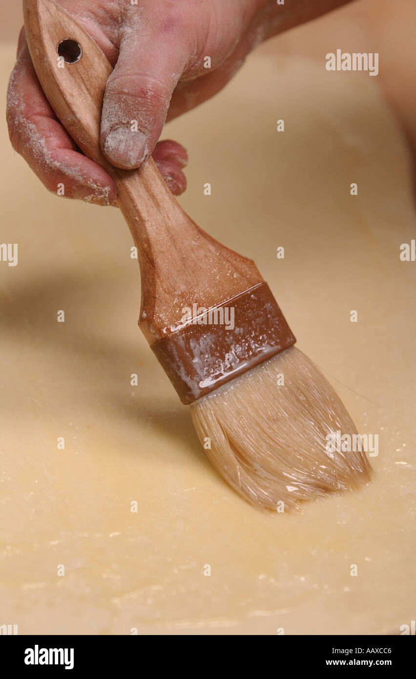 Baker pintura mantequilla en masa en una panadería con una brocha. Foto de stock