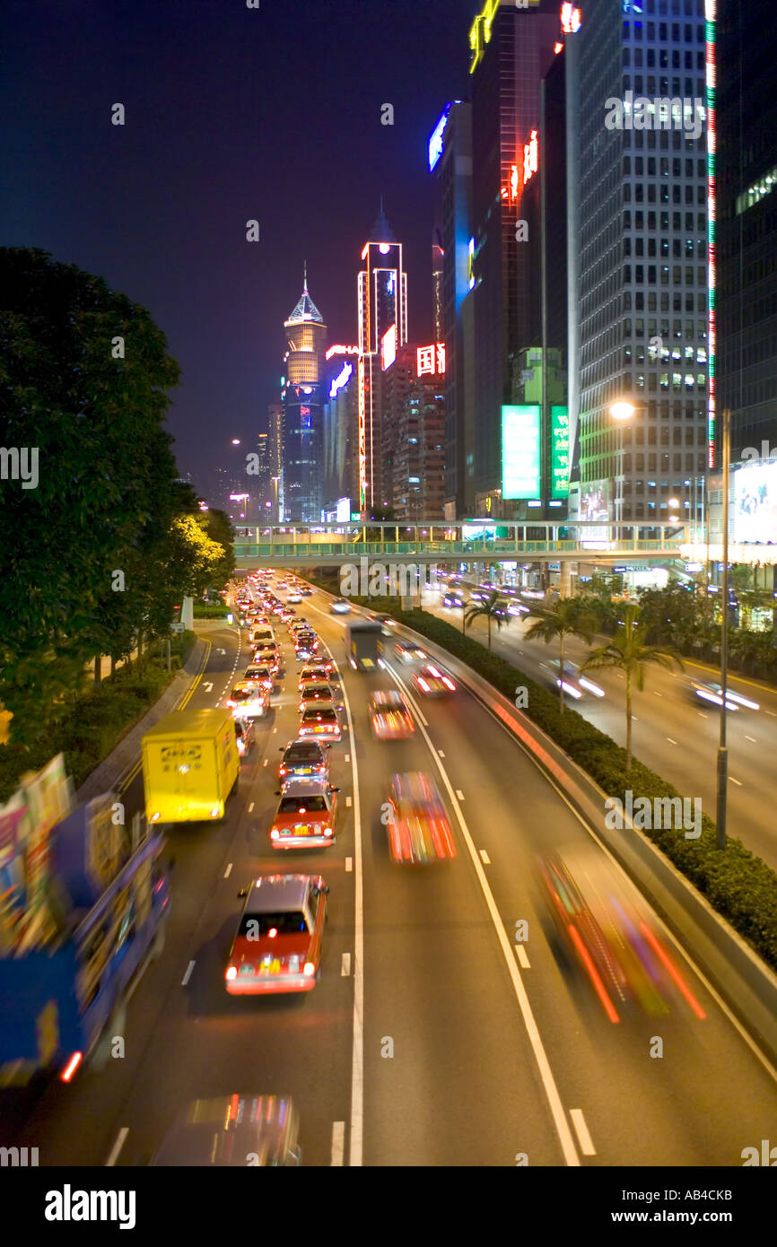 Una vista de los rascacielos y el tráfico con el desenfoque de movimiento y estelas de luz a lo largo de Gloucester Road en la isla de Hong Kong por la noche Foto de stock