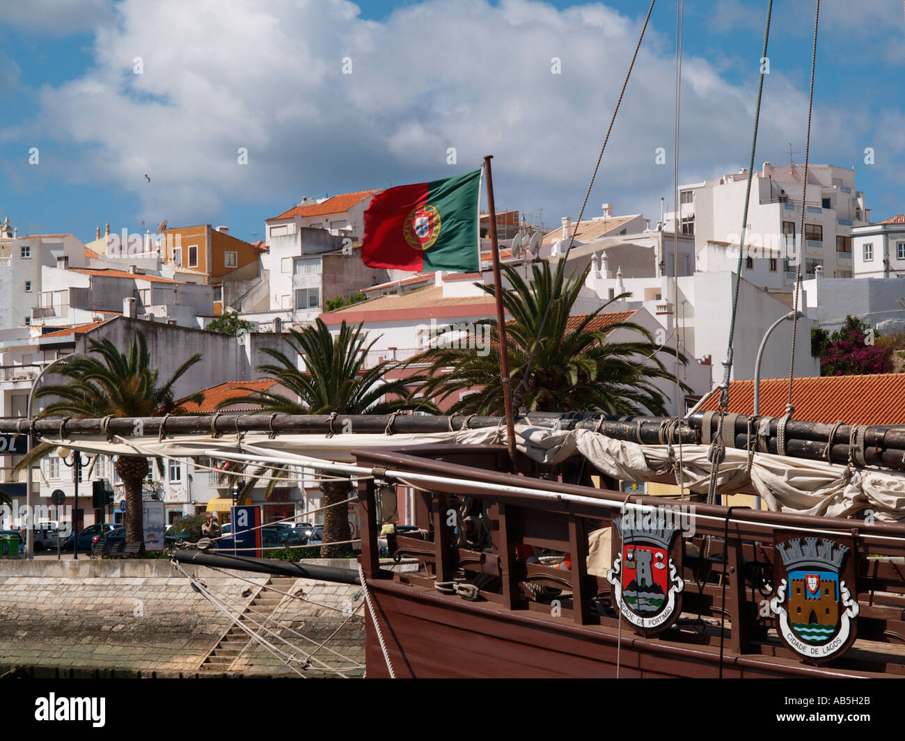 Lagos Algarve portugués de Portugal bandera en CARAVELA STERN amarrado en el río de la entrada a la marina de Lagos con edificaciones Foto de stock