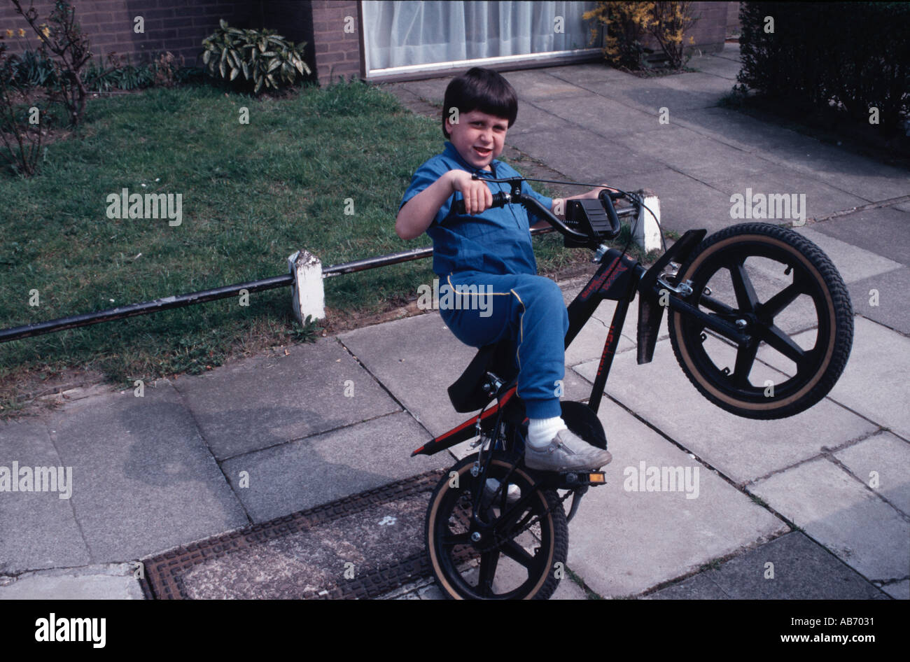 Niño pequeño en una bicicleta del picador haciendo un caballito 1980 Foto de stock