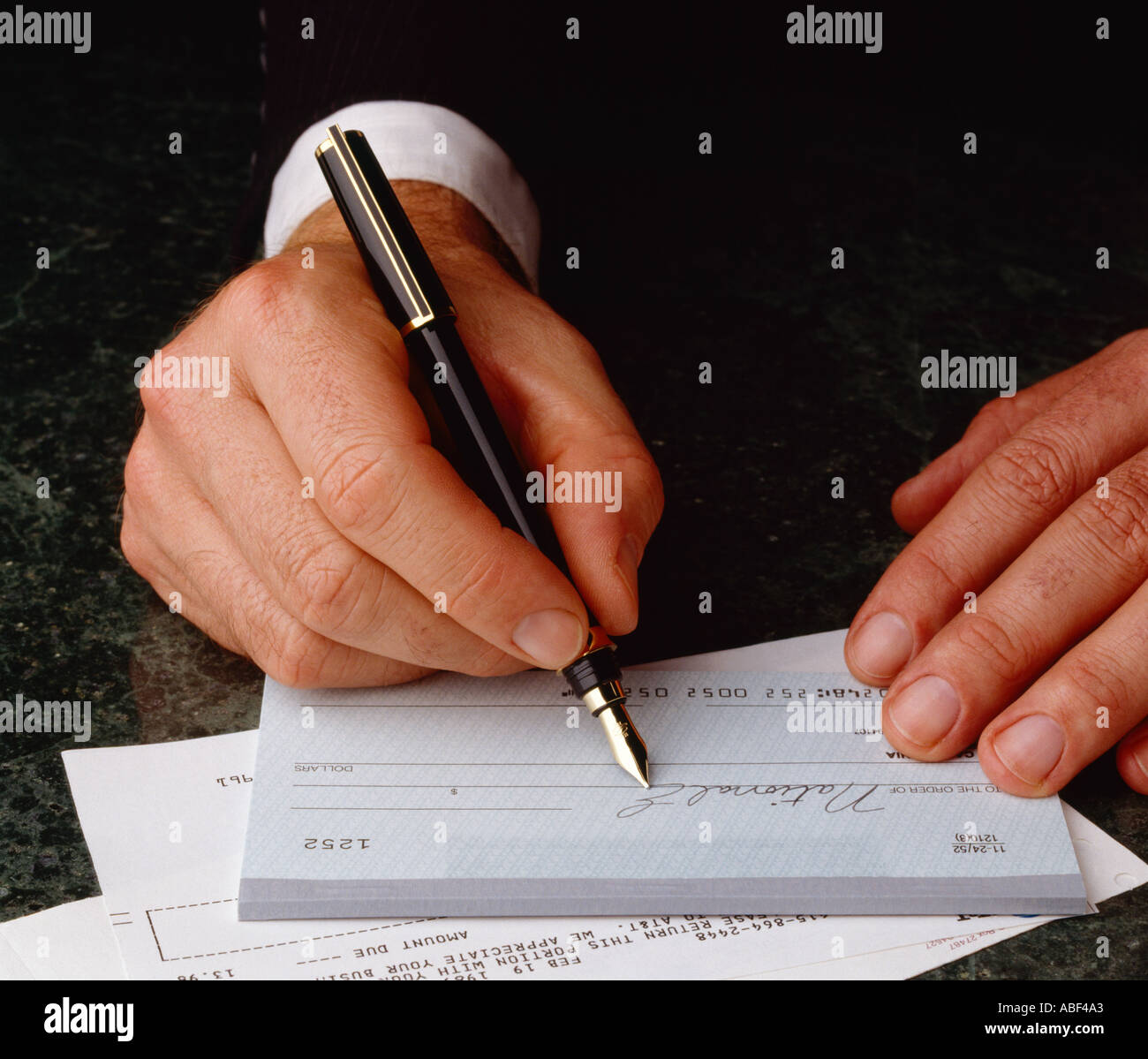 Financieros - Manos de un empresario de escribir un cheque. Foto de stock