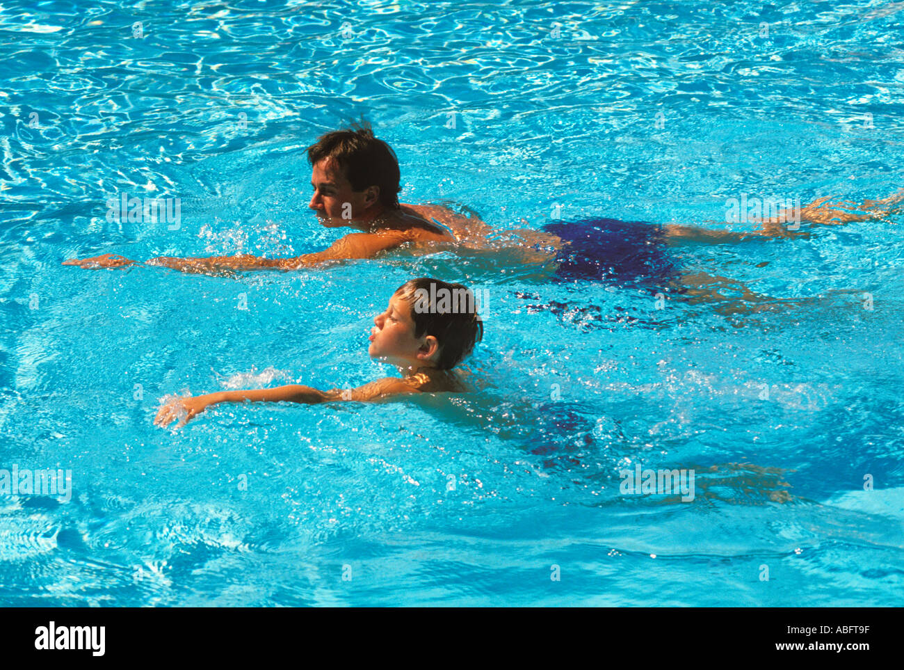 Un padre da una lección de natación a su hijo de nueve años Foto de stock