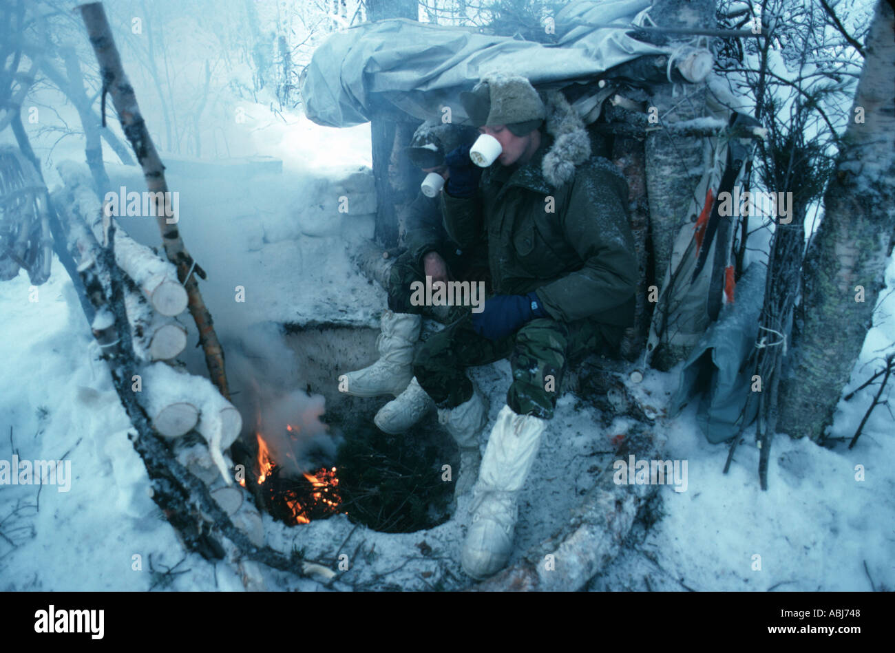 Soldados en ejercicio de supervivencia en el círculo polar ártico mantenerse caliente con fuego Foto de stock