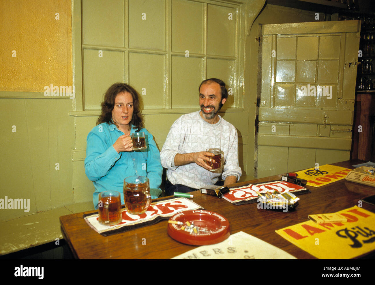El hombre y la mujer 40s de bebedores de cerveza en un pub inglés circa 1985 Foto de stock