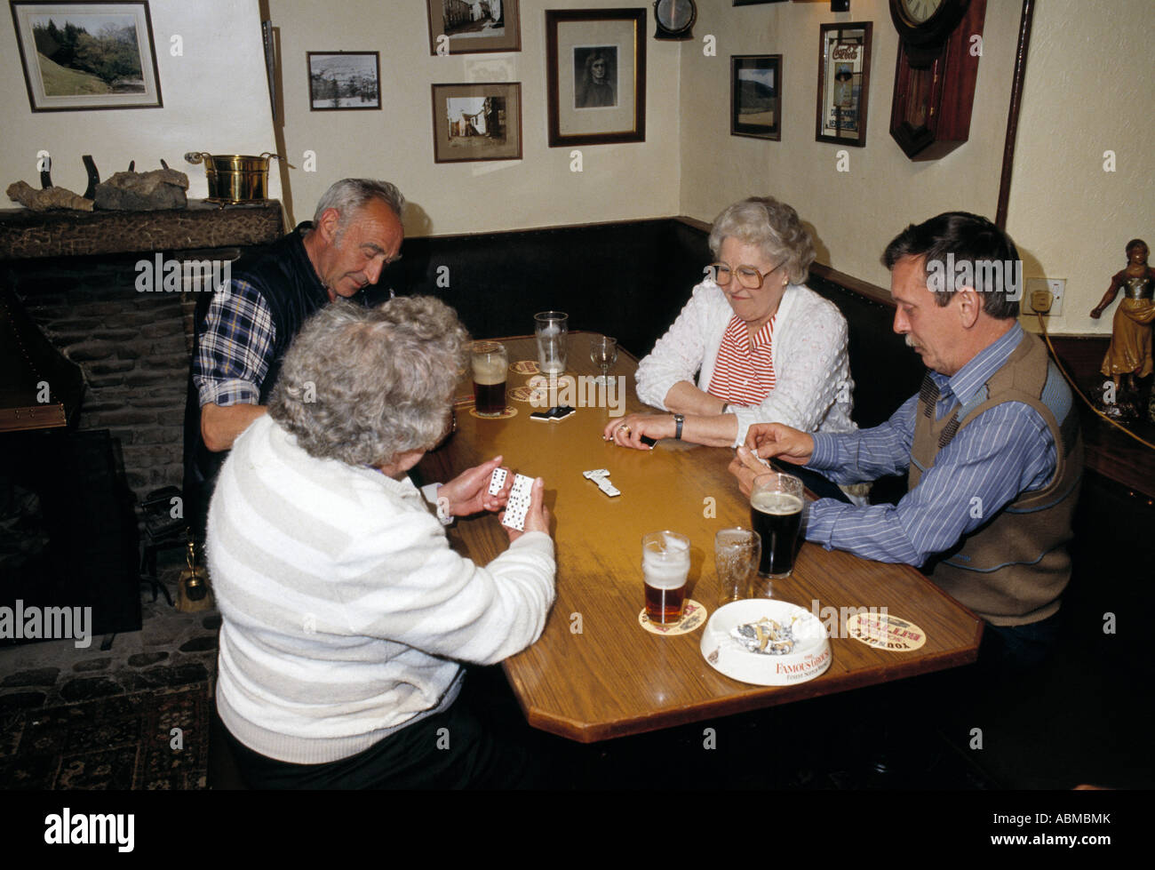 Hombres y mujeres disfruten de un juego de dominó en un pub tradicional en el norte de Inglaterra en 1980. Foto de stock