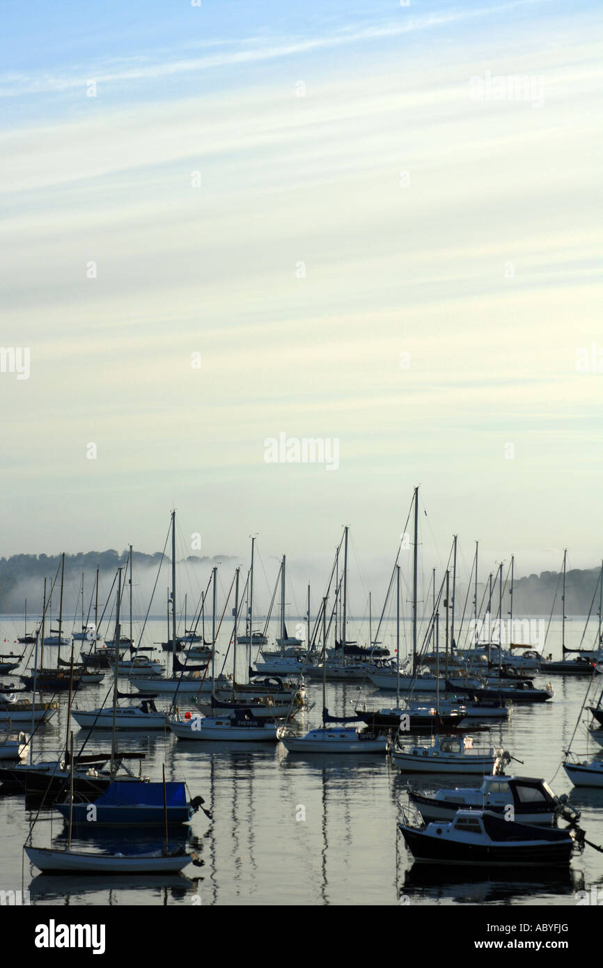 Barcos amarrados al amanecer con niebla por la mañana temprano en Falmouth Harbour Mylor Devon Foto de stock