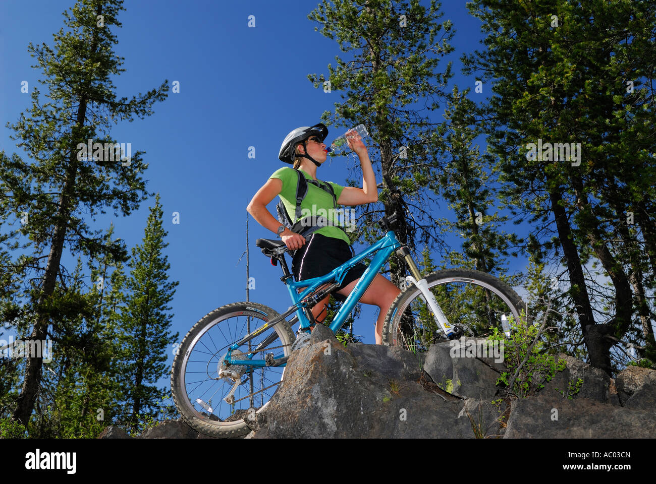 Ciclista de montaña femenino tomando una bebida en la cima de un acantilado Foto de stock