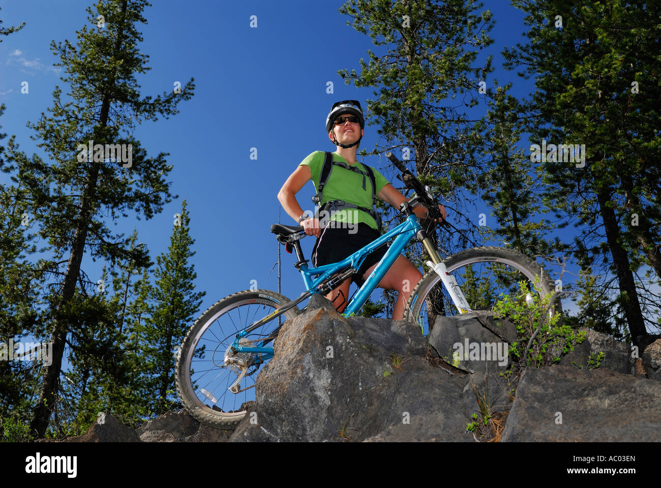 Ciclista de montaña femenino ver la escena en la cima de un acantilado con árboles de hoja perenne y un cielo azul Deschutes National Forest Oregon Foto de stock