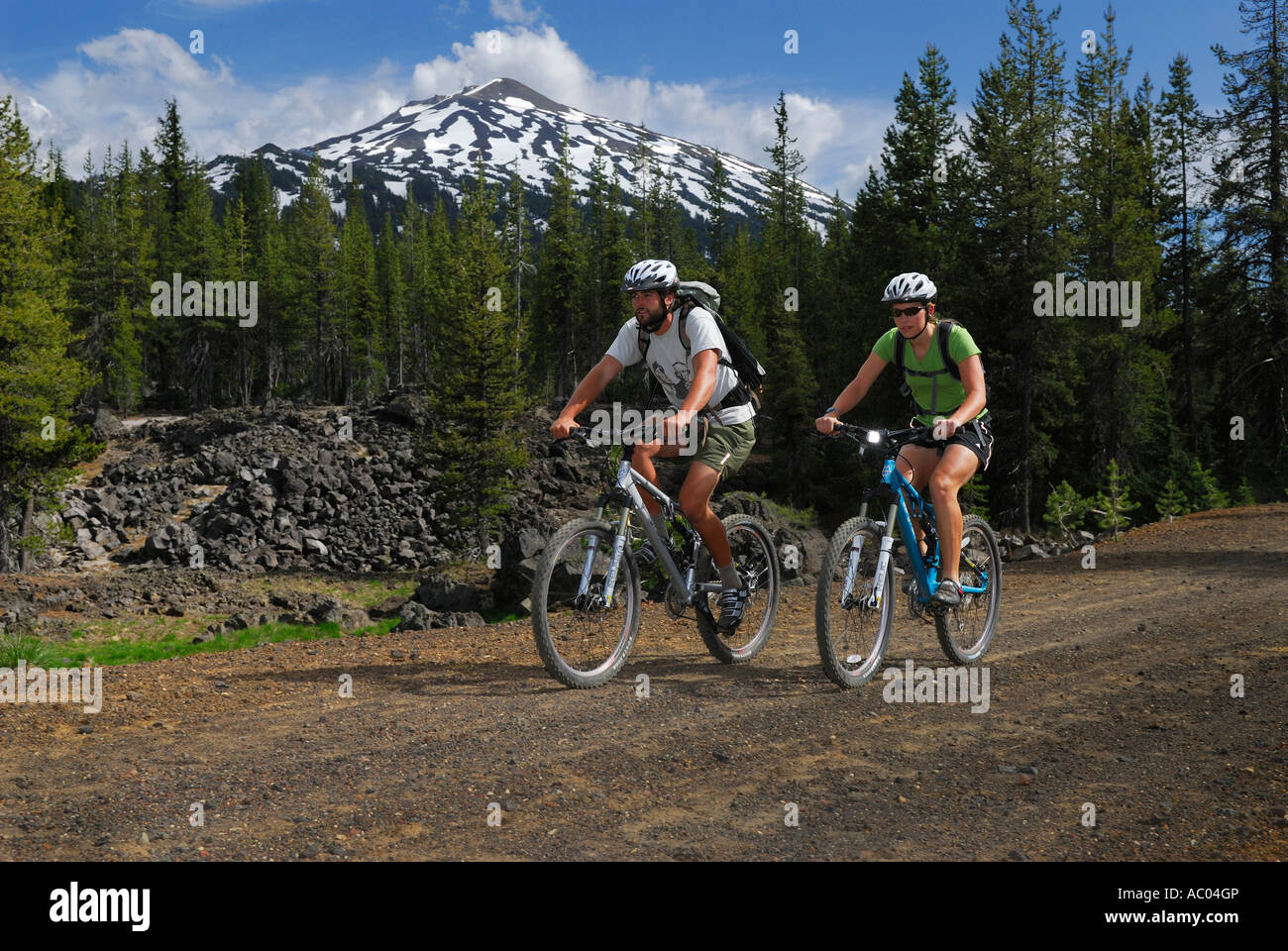 Los ciclistas de montaña en cascos viajar un camino de tierra bajo nevado Mount Bachelor Oregón EE.UU. Foto de stock