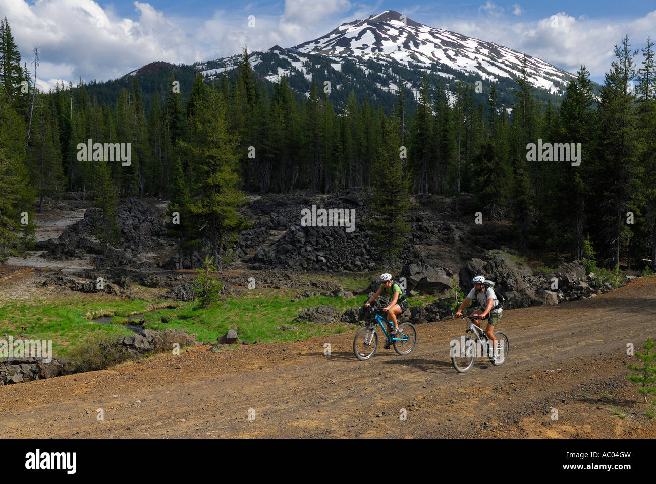 Los ciclistas de montaña de andar por un camino de tierra bajo nevado Mount Bachelor Oregón EE.UU. Foto de stock