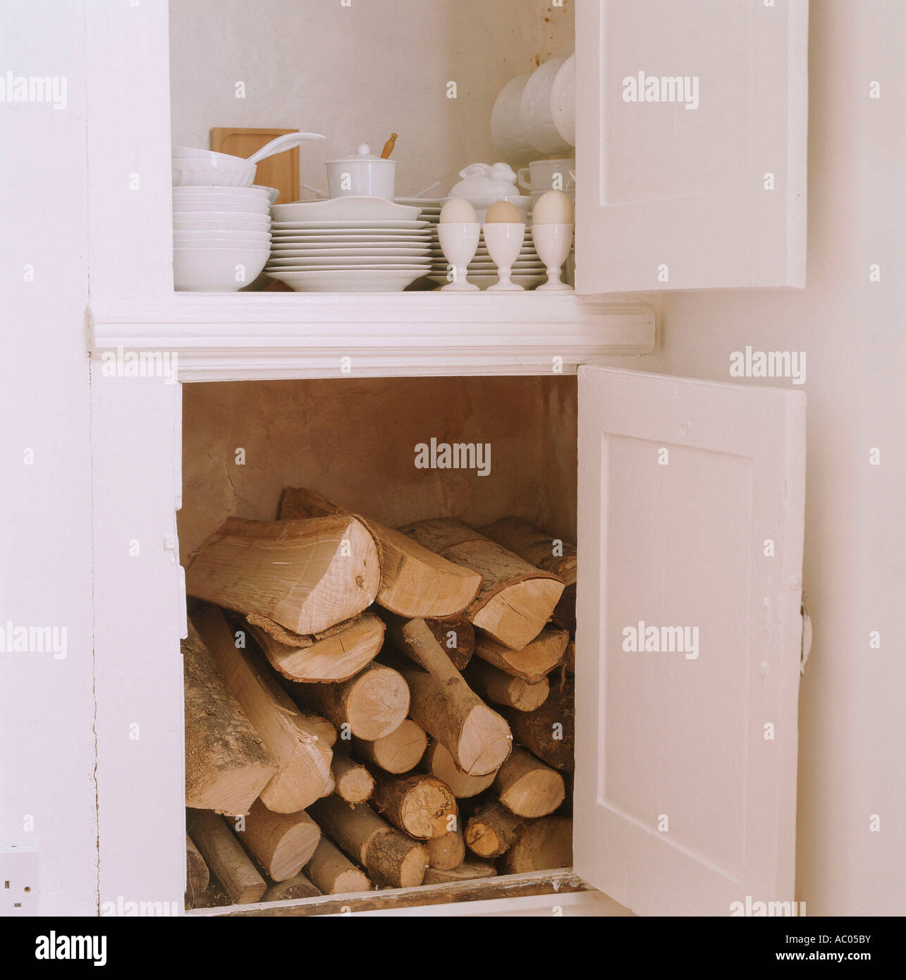 Cocina abierta con armarios de almacenamiento de leña para el fuego y vajilla Foto de stock