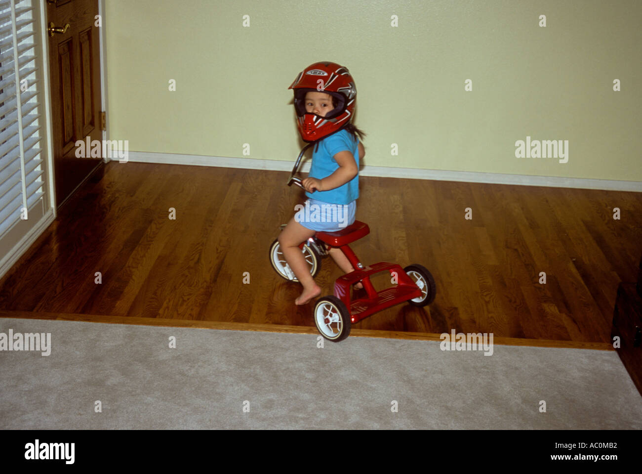 3 o 4 años niña en un triciclo vistiendo un casco de motocross Fotografía  de stock - Alamy
