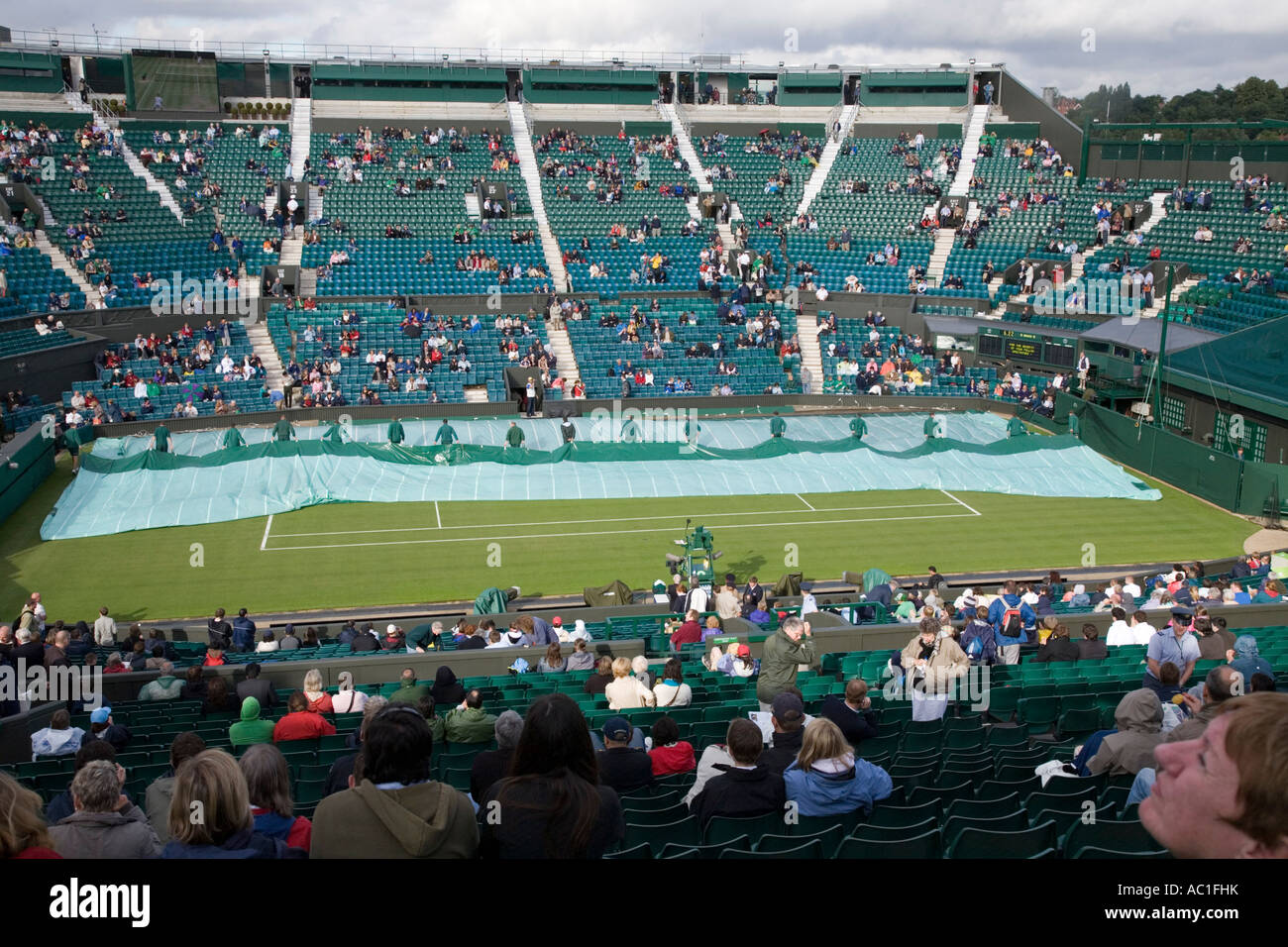 Cubiertas retiradas durante Carlos Moya Tim Henman en el centro de la cancha de juego sin techo durante el Campeonato de tenis de Wimbledon Foto de stock