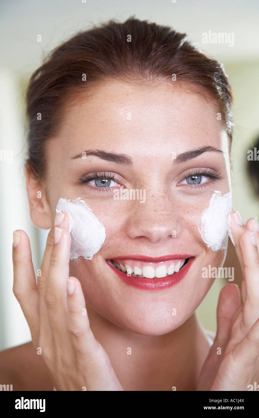 Mujer joven de aplicar crema para la cara Foto de stock