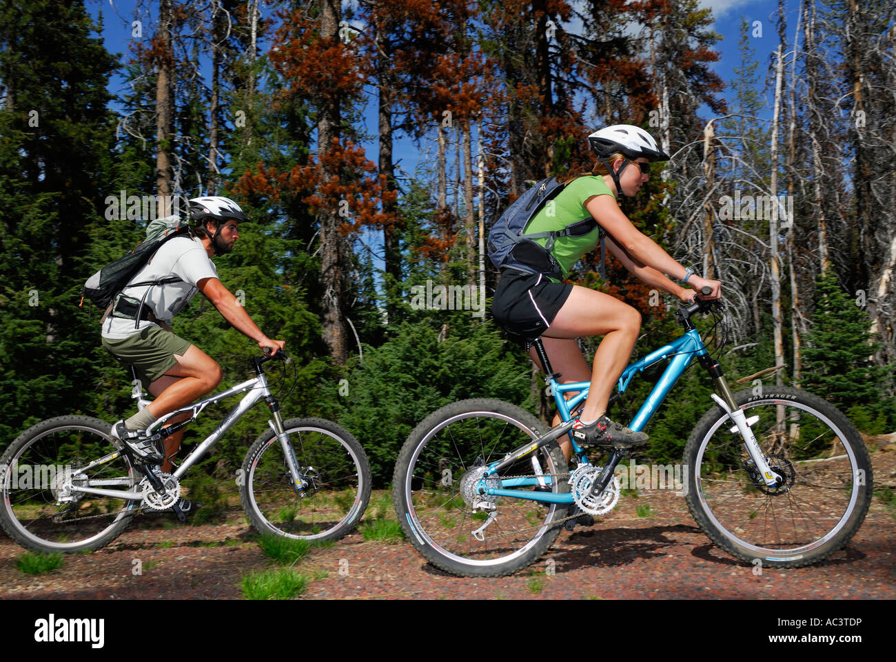 Un par de ciclistas de montaña con cascos en camino a través del bosque en chispas Lago Oregón EE.UU. Foto de stock
