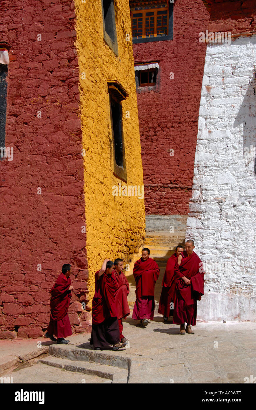Los monjes tibetanos caminando por el ocre rojo y paredes pintadas de blanco el Monasterio Ganden Tibetano China Foto de stock