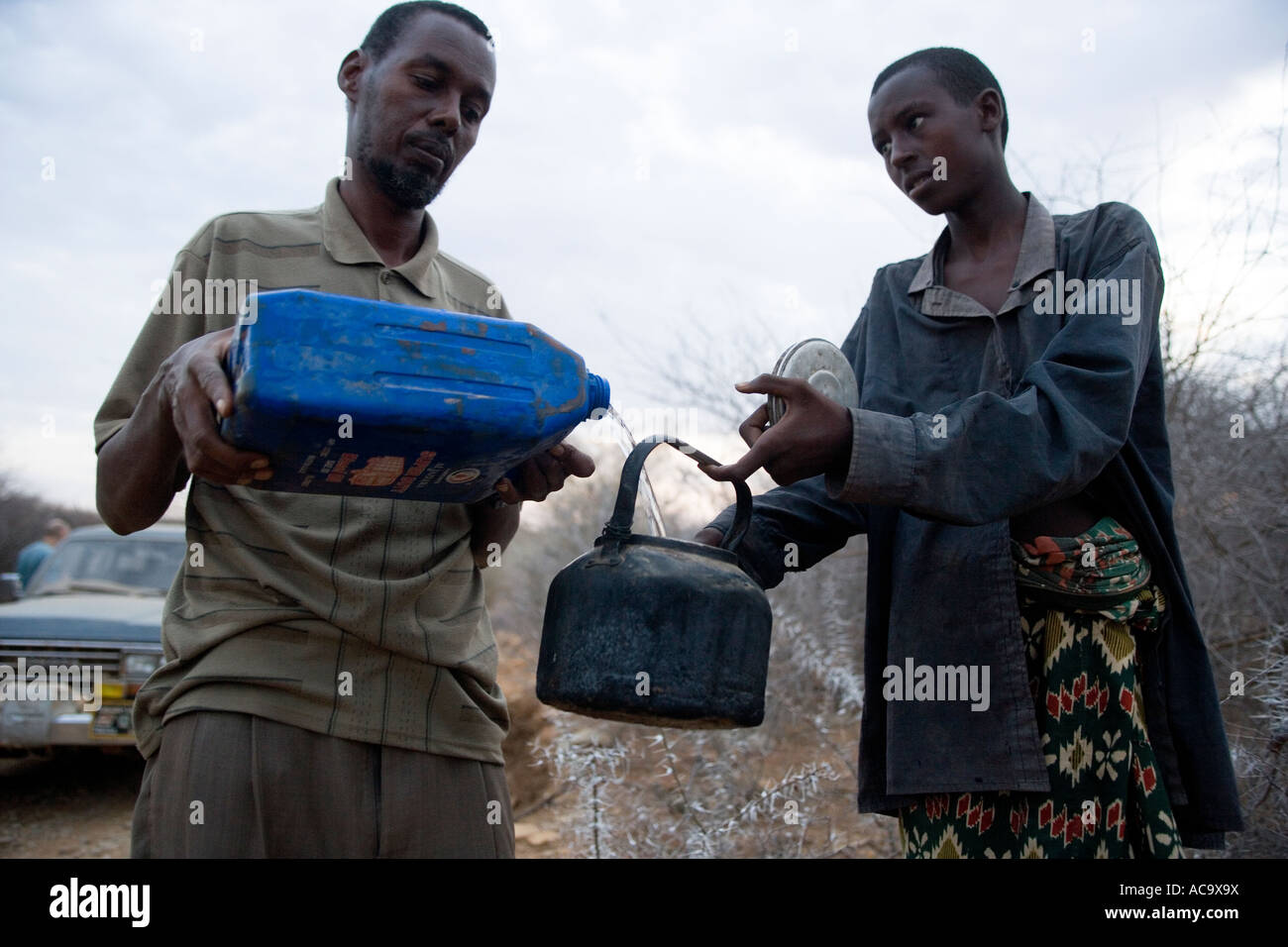 SOMALIA OCCIDENTAL 2 de marzo de 2006 un conductor da agua a un nómada pidiendo agua por el lado de la carretera Foto de stock