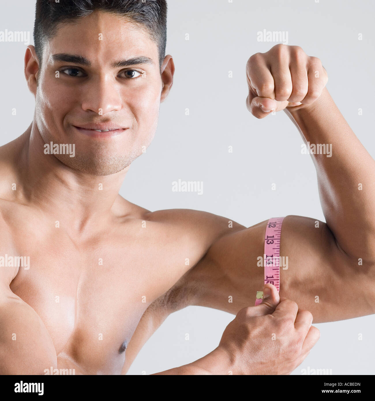Retrato de un joven midiendo sus bíceps con una cinta métrica Fotografía de  stock - Alamy